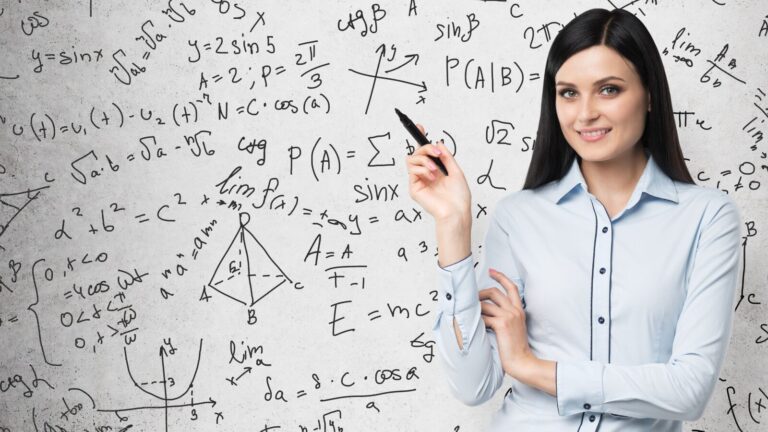 Woman in light blue shirt holding a pen, standing in front of a wall covered with mathematical equations and formulas